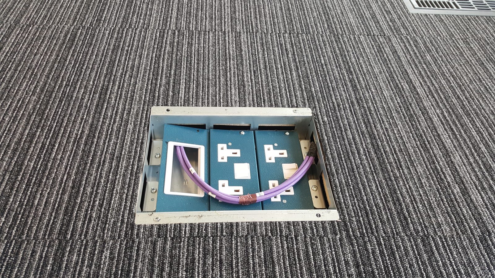 Floor box installation providing power and data outlets within a commercial carpeted floor.